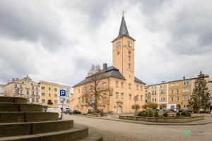 un bâtiment avec une tour d'horloge au milieu d'une rue dans l'établissement Apartament w Rynku I, MyWeek, à Radków