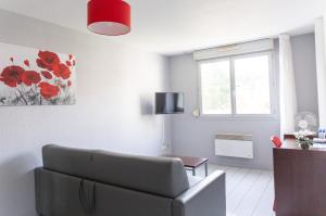 - un salon avec un canapé et une fenêtre dans l'établissement Zenitude Hôtel-Résidences La City, à Besançon