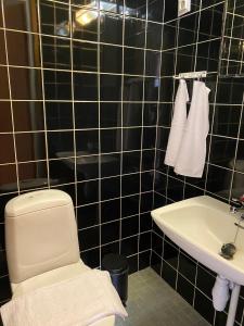 Baño de azulejos negros con aseo y lavamanos en Kolme makuuhuonetta Merenrannalla Lauttasaaressa, en Helsinki