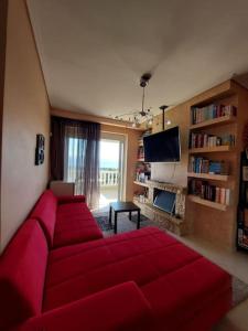 salon z czerwoną kanapą i telewizorem w obiekcie Διαμερισμα με θεα Ερετρια w Erétrii