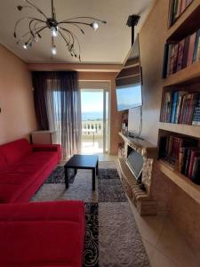 salon z czerwoną kanapą i telewizorem w obiekcie Διαμερισμα με θεα Ερετρια w Erétrii