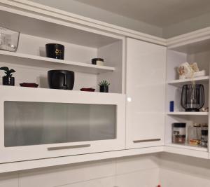 a kitchen with white cabinets and a microwave at Stan Ideja in Novi Sad +7 photos