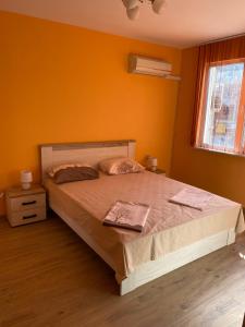 - une chambre avec un grand lit aux murs orange dans l'établissement Апартамент за гости ДИГЕНА, à Kazanlak
