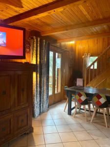 a living room with a table and a television in a cabin at Le refuge, chalet au pied des pistes au Sauze in Enchastrayes