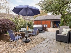 a patio with a table and chairs and an umbrella at Foxglove Barn in South Brent