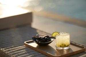 a tray with a drink and a bowl of olives at Danae Suites Santorini in Oia