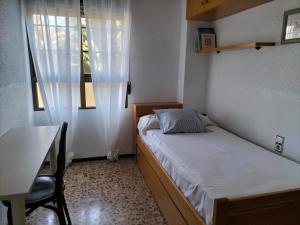 1 dormitorio con cama, mesa y ventana en Piso Centro María Aire-Wifi en Elche