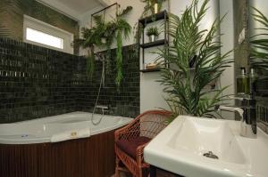 bagno con vasca, lavandino e piante di Boutique Villa Gyula a Gyula