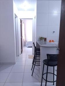 a kitchen with a counter and chairs in a room at Cantinho arretado da Peste - Apartamento in Aquiraz