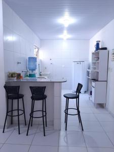 a kitchen with three bar stools and a counter at Cantinho arretado da Peste - Apartamento in Aquiraz