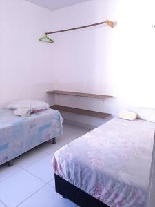a room with two beds and a shelf in it at Cantinho arretado da Peste - Apartamento in Aquiraz
