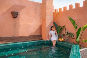 una donna seduta in acqua accanto a una piscina di Riad Lalla Mimouna a Marrakech