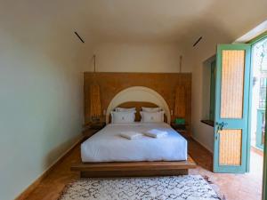 1 dormitorio con cama blanca y puerta azul en Riad Lalla Mimouna en Marrakech