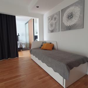 a bedroom with a bed with an orange pillow on it at Rubita Apartments in Pärnu
