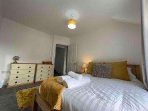 um quarto com uma grande cama branca e uma cómoda em Modern 2 BR Flat in Town Centre em Aberystwyth