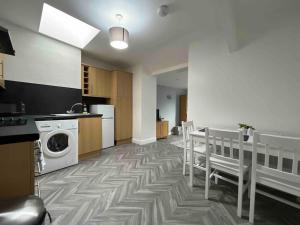 uma cozinha com uma máquina de lavar roupa, uma mesa e cadeiras em Modern 2 BR Flat in Town Centre em Aberystwyth