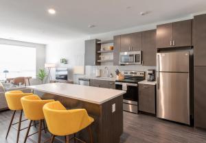 a kitchen with stainless steel appliances and yellow bar stools at Cozysuites l Stylish 1BR in Downtown Cincinnati in Cincinnati