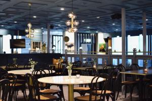 a dining room with tables and chairs and windows at Vätterledens Stugrum in Gränna
