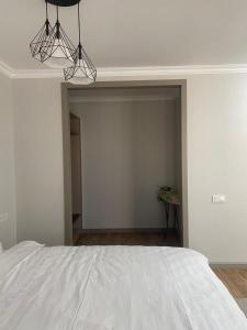 a bedroom with a white bed and two lights at 71 East Apart Hotel in Prigorodnyy