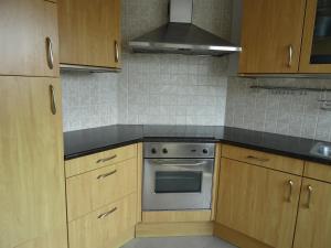 a kitchen with wooden cabinets and an oven at Kustverhuur, Dorpswoning Breskens, Boulevard 15 in Breskens