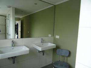 a bathroom with two sinks and a mirror at Kustverhuur, Dorpswoning Breskens, Boulevard 15 in Breskens +14 photos