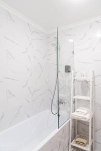 a bathroom with a shower with white marble walls at 71 East Apart Hotel in Prigorodnyy
