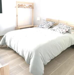 uma cama grande com lençóis brancos e almofadas em Encantadora casa rural Can Vidal em Espolla