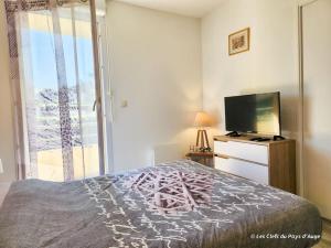 una camera con letto, TV e finestra di Bel F3 en résidence avec piscine, baignoire balnéo a Touques