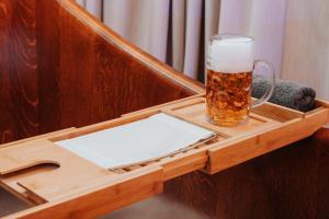 a glass of beer sitting on a wooden tray at Wellness Hotel Smaragd Piešťany in Piešťany