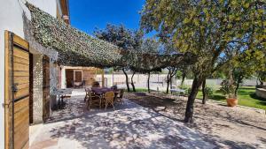 d'une terrasse avec une table et des chaises sous un arbre. dans l'établissement Mas de la Roncière, à Sorgues