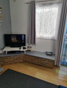 a living room with a flat screen tv sitting under a window at Yorkie's place in Bessingby