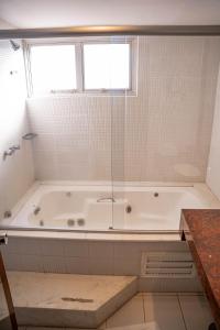 a bathroom with a bath tub with a window at Black Stream Hotel in Ribeirão Preto