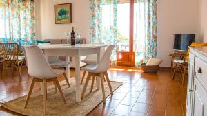 Casa Baddò, fronte spiaggia A/C في كالا غونوني: مطبخ وغرفة طعام مع طاولة وكراسي بيضاء