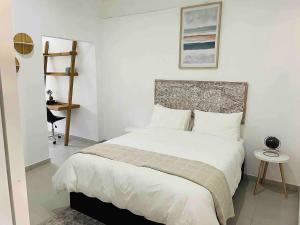 a bedroom with a large white bed with a headboard at Ultra modern 2 bedroomed apartment - 2082 in Bulawayo