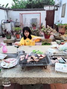 una mujer está cocinando comida en una parrilla en Sunny's Home en Jincheng