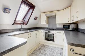 a kitchen with white cabinets and a sink at Double room 2 mins from station in Belvedere