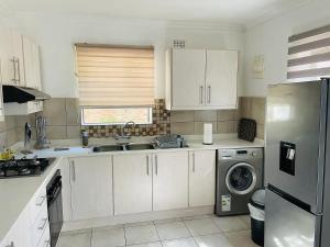 a kitchen with white cabinets and a stainless steel refrigerator at Mellow 2 bedroomed cottage - 2083 in Bulawayo