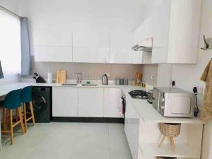 cocina con armarios blancos, fregadero y microondas en Contemporary 2 bed in Suburbs - 2080, en Bulawayo