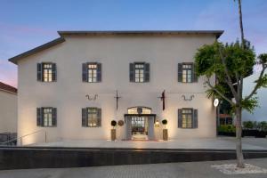 un gran edificio blanco con un árbol delante en Rephael House Boutique Hotel, en Rishon LeZion