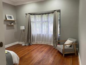 1 dormitorio con 1 cama y ventana con silla en Modern Apartment - 2081, en Bulawayo