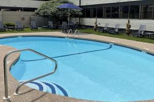 納西瓦的住宿－Clarion Inn，一个带椅子和遮阳伞的大型蓝色游泳池