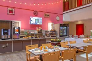 ein Restaurant mit Tischen und Stühlen und einer rosa Wand in der Unterkunft SOWELL RESIDENCES New Chastillon in Isola 2000