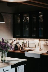 - une cuisine avec des placards noirs et un évier blanc dans l'établissement La Maison Perchée, à Thiers