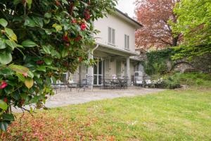 uma casa branca com uma mesa e cadeiras num quintal em Bnbook Maison Charlotte Lago Maggiore em Porto Valtravaglia