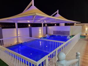 a house with a swimming pool with an umbrella at سمارت شاليه: Smart Chalet in Salalah