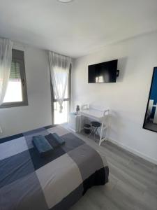 a bedroom with a bed and a desk and a television at Casa Uma in Corralejo +26 photos