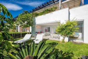 マルベーリャにあるMarbella Golf y Beach Santa Clara By Houselogyの白い家具が置かれた裏庭、植物の植えられた庭