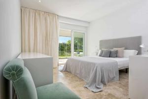 マルベーリャにあるMarbella Golf y Beach Santa Clara By Houselogyの白いベッドルーム(ベッド1台、椅子付)