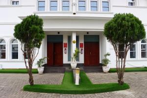 a white building with two red doors and three trees at PRESKEN WHITE HOUSE in Lagos