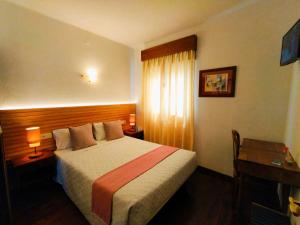 ein Hotelzimmer mit einem Bett, einem Schreibtisch und einem Fenster in der Unterkunft Casa Hóspedes Polido in Termas de Sao Pedro do Sul